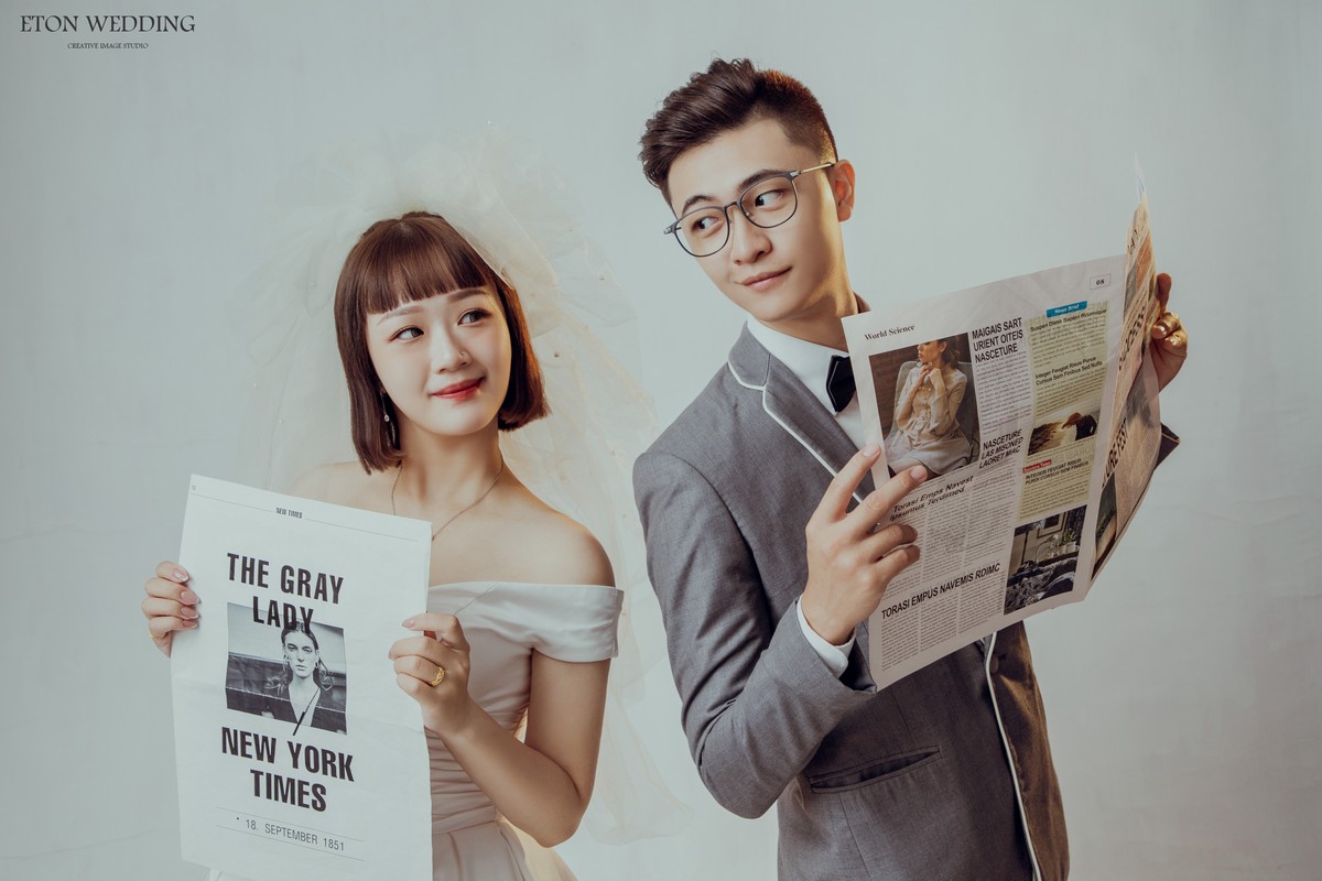 一個短髮可愛新娘跟新郎手上拿著報紙，互相對視的可愛婚紗照