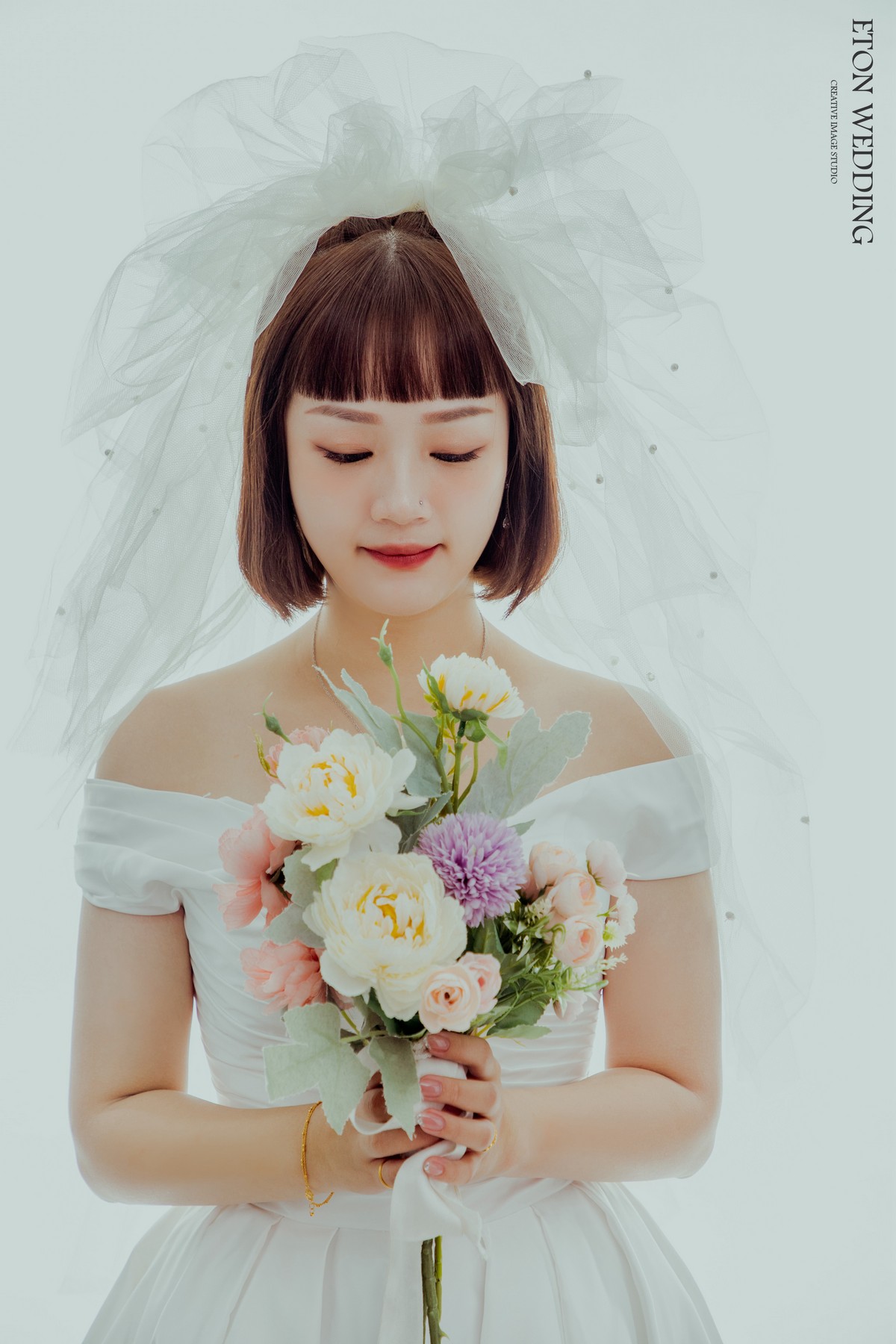 一個短髮可愛新娘手上拿著一束捧花的可愛婚紗照